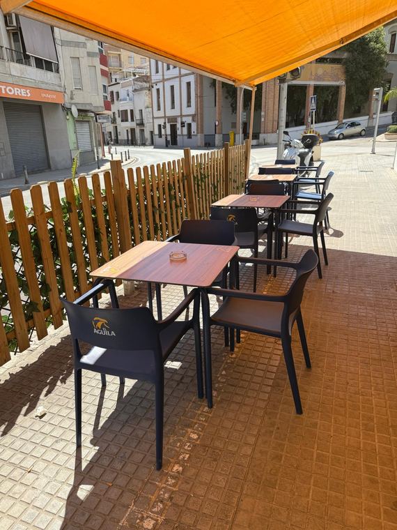 Terraza de Bar Sanchis con toldo naranja y mesas al sol